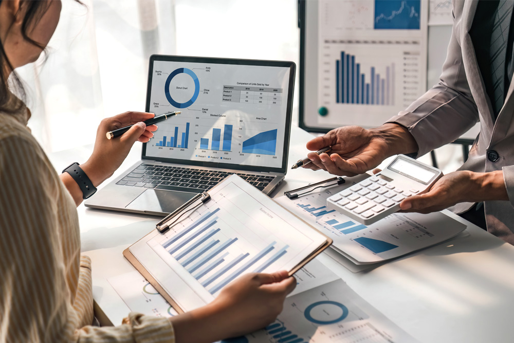 Auf diesem Bild sehen wir eine Unternehmerin und einen Bankberater die sich gemeinsam Statistiken des Unternehmens und die Zahlen anschauen um einen Kredit zu ermöglichen für Finanzierungen.