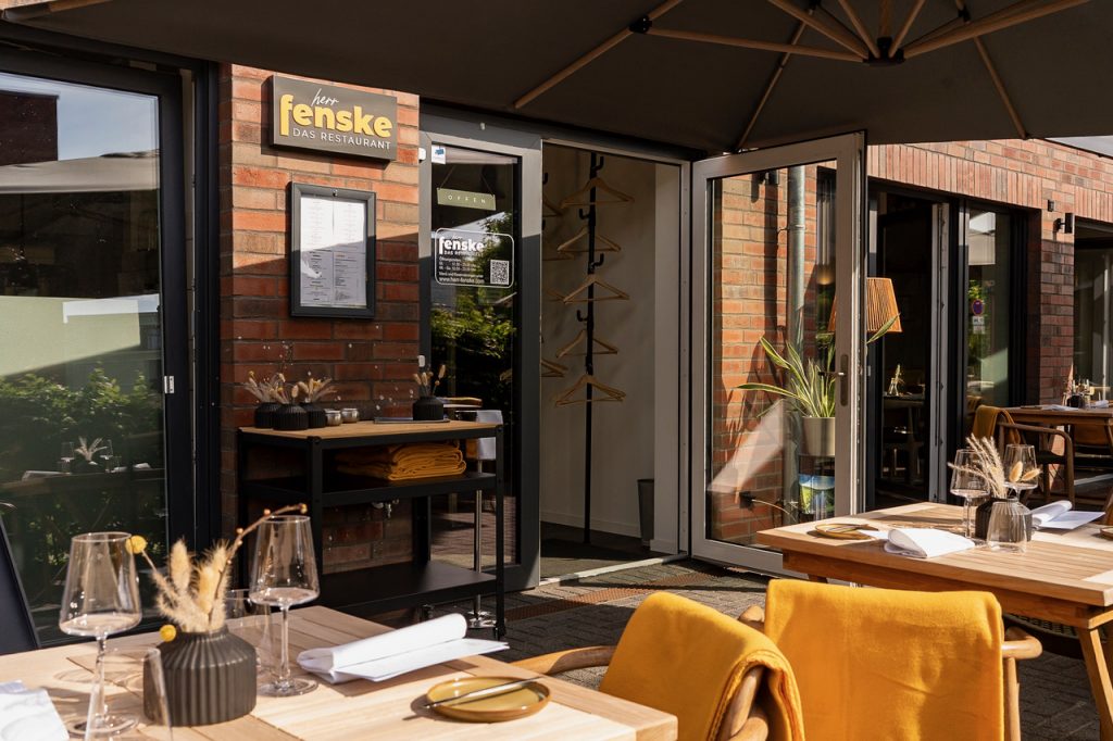 Eingangsbereich des Restaurants Herr Fenske in Neuruppin mit Außenterrasse und modernem Gastronomiekonzept.