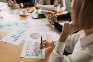 Personen die vor Statistiken sitzen und dar&uuml;ber sprechen